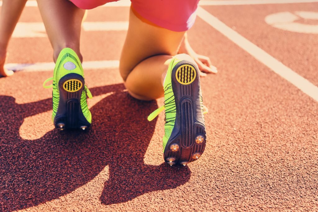 Blond sporty female runner quick start position stadium
