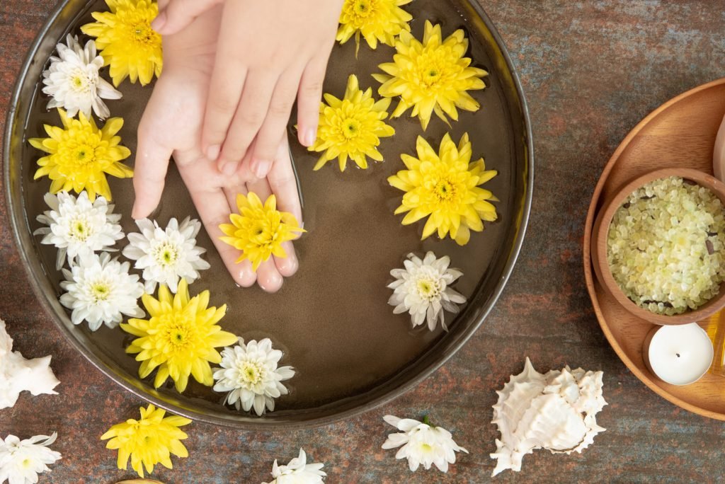 Female hands bowl spa water with flowers close up hands spa