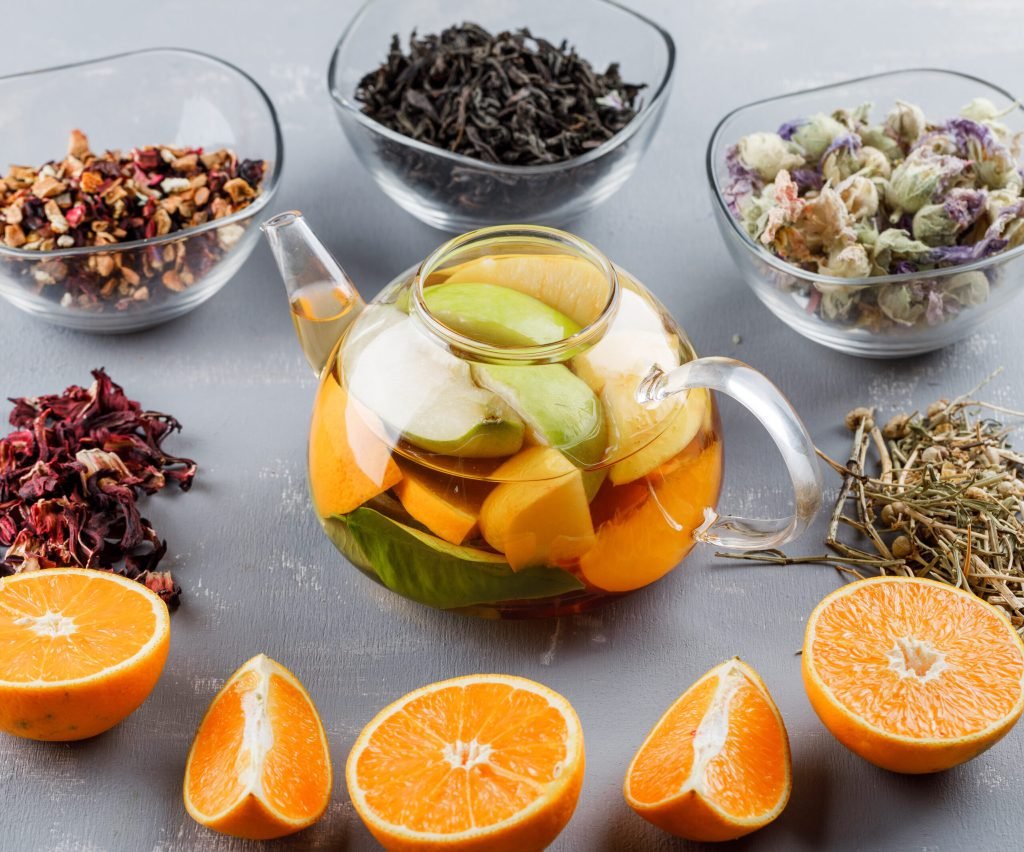 Fruit infused water teapot with herbs oranges high angle view plaster surface