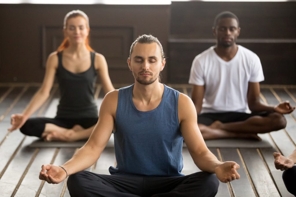 Group young sporty people sitting sukhasana exercise