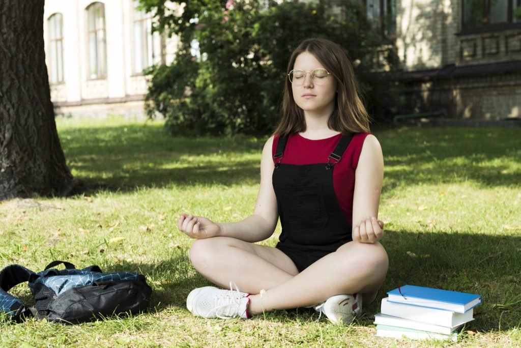 Sideview meditating highschool girl