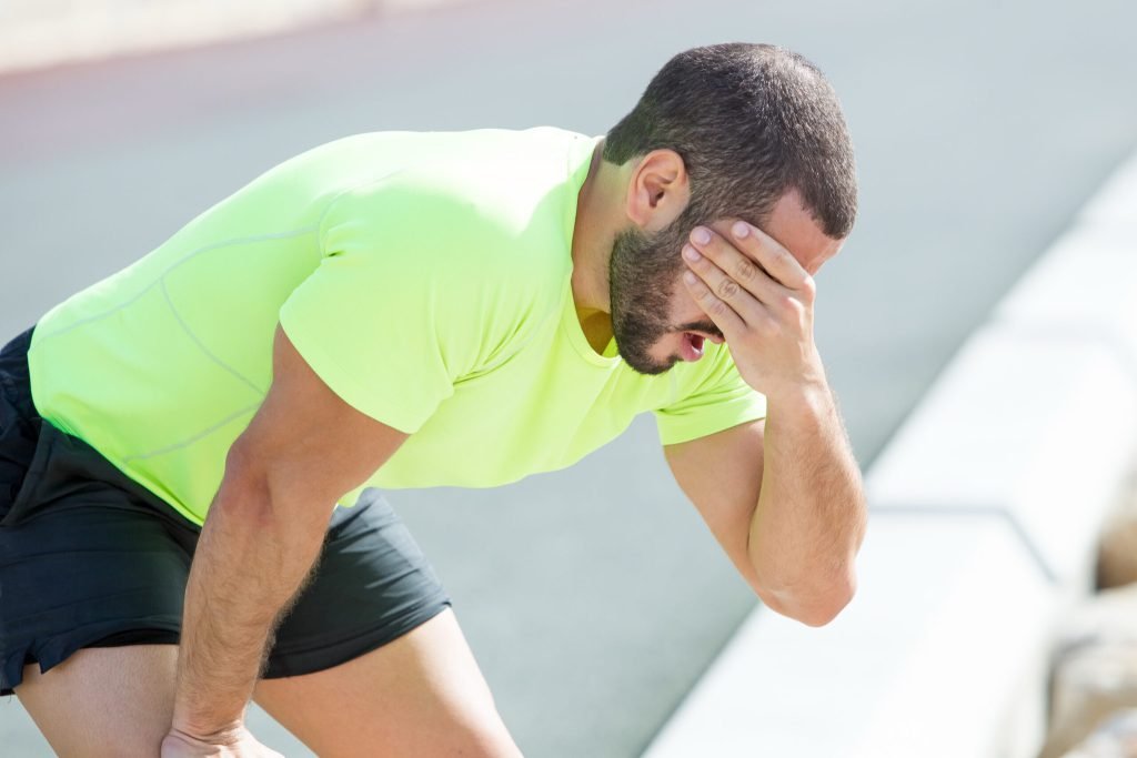 Tired sporty man relaxing covering face
