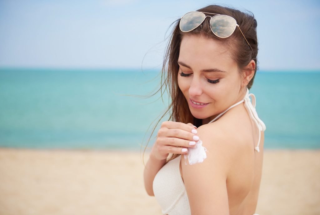 Young beautiful woman applying sun cream beach