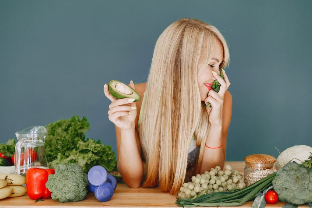 Beautiful girl make salad sporty blonde kitchen woman with avocado