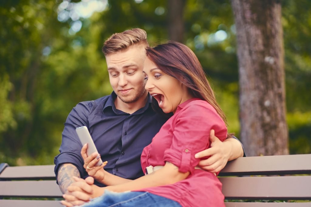 Couple date city park using smartphone instant messaging