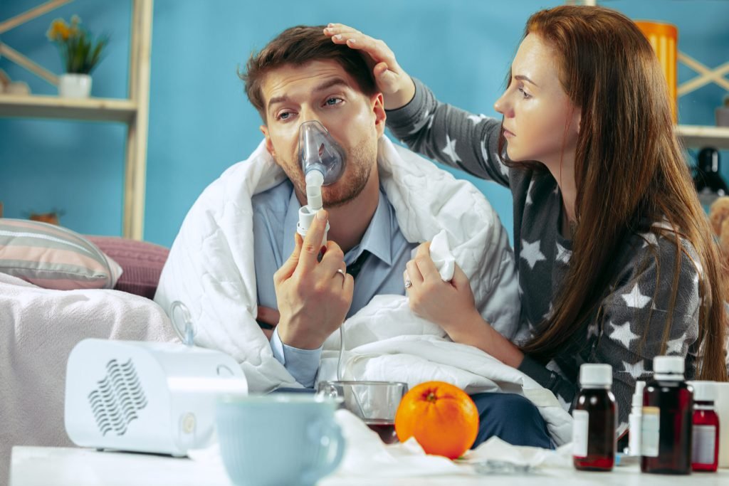 Sick man with fever lying bed having temperature his wife take care him illness influenza pain family concept relaxation h...