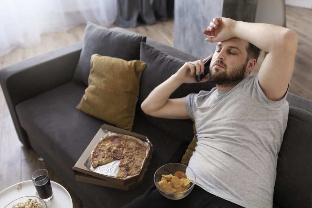 Young man eating junk food home sofa