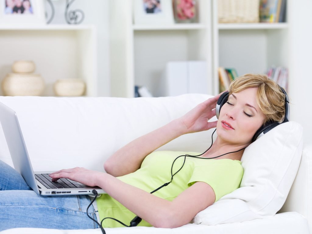 Beautiful woman sofa with laptop listening music headphone indoors