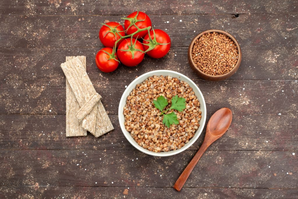 Top view cooked tasty buckwheat inside plate with crisps red tomatoes dark