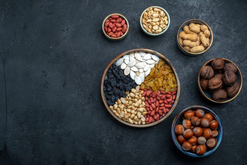 Top view different nuts with raisins dried fruits dark grey background nut snack hazelnut walnut peanut