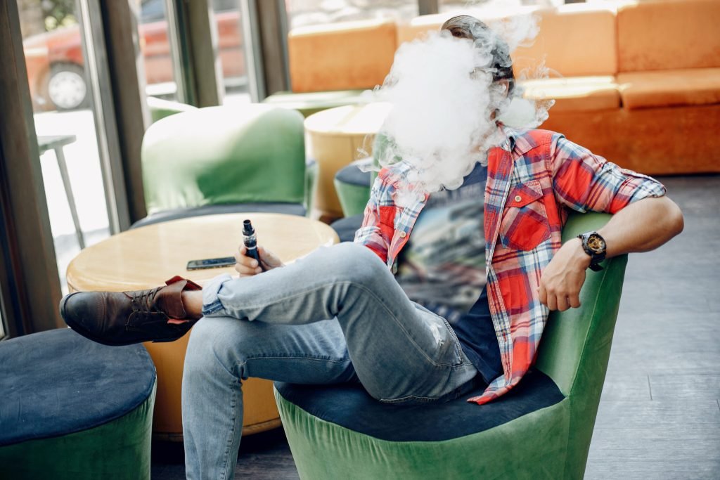 Stylish elegant man sitting cafe with vape