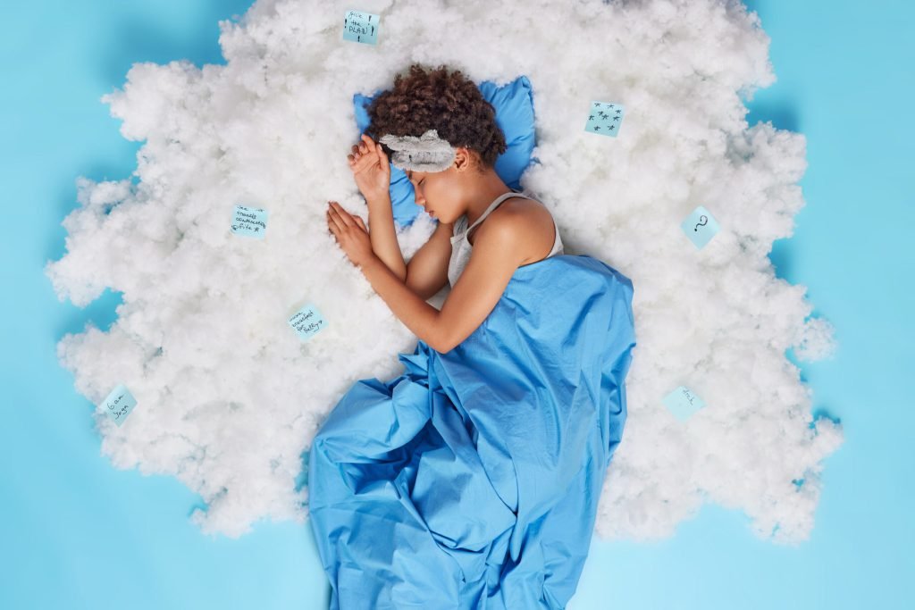 Relaxed curly haired afro american woman sleeps well has sweet dreams