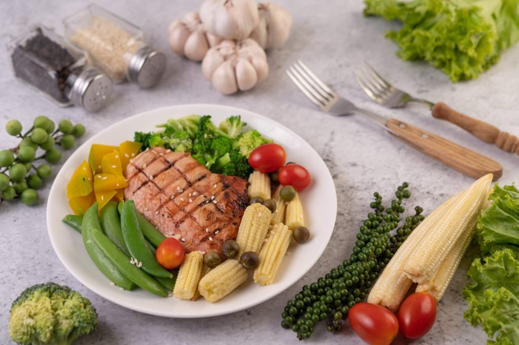 Chicken steak topped with white sesame peas tomatoes broccoli pumpkin white plate