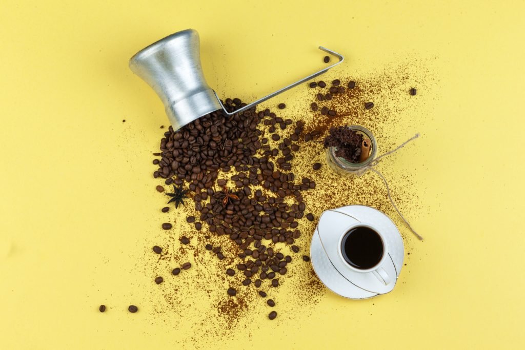 Coffee beans jug with glass jar cup coffee flat lay yellow background
