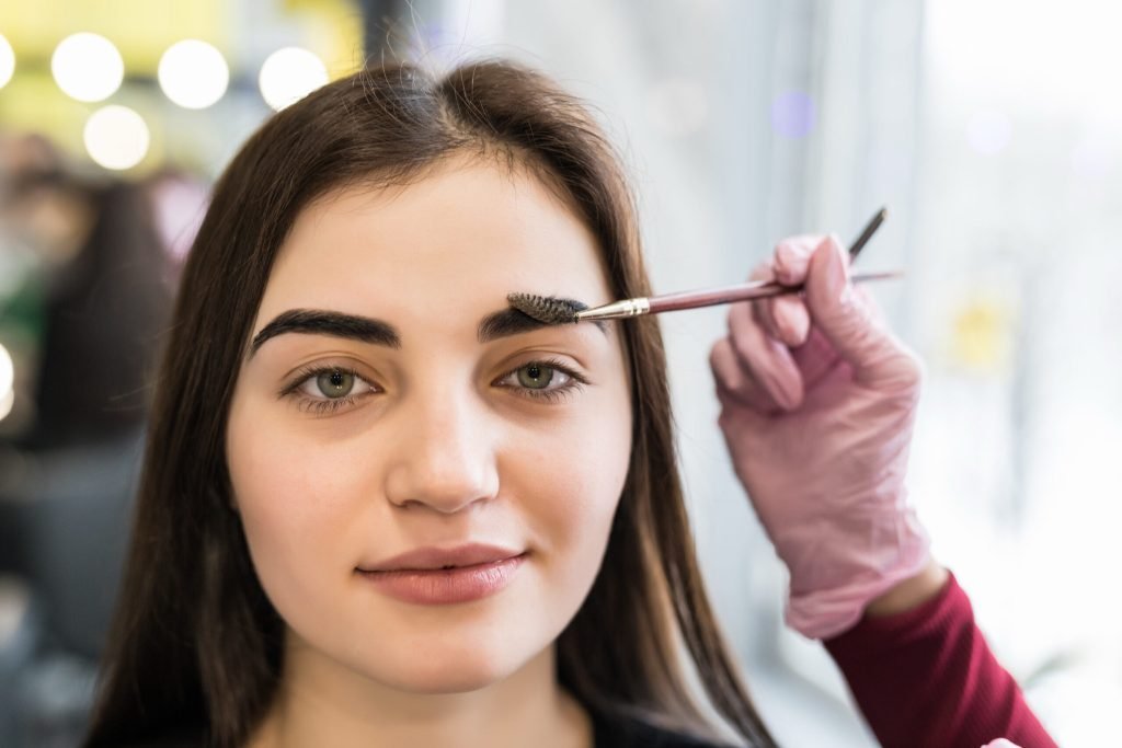 Master doing final steps make up model with green eyes