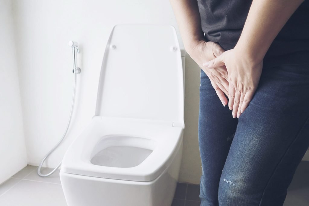 Woman holding hand near toilet bowl health problem concept