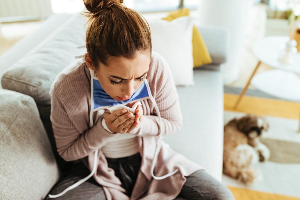 Young woman using paper tissue coughing while being home