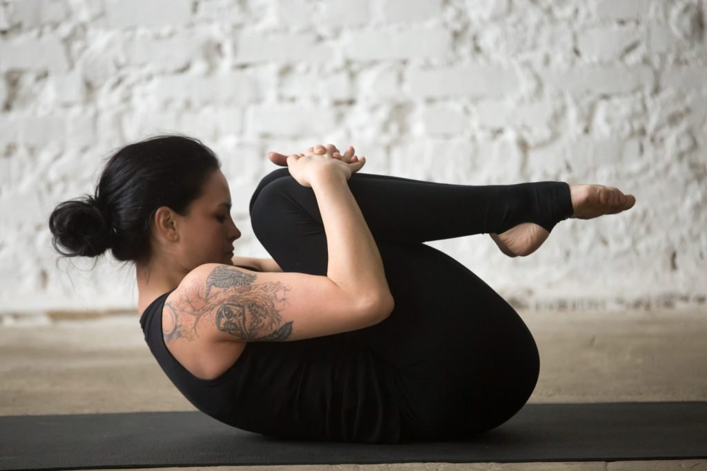 Young yogi attractive woman knees chest pose studio