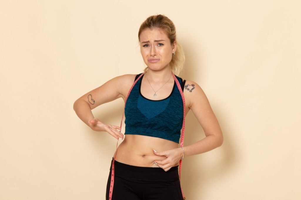 Front view young female sport outfit measuring her body sad due her weight