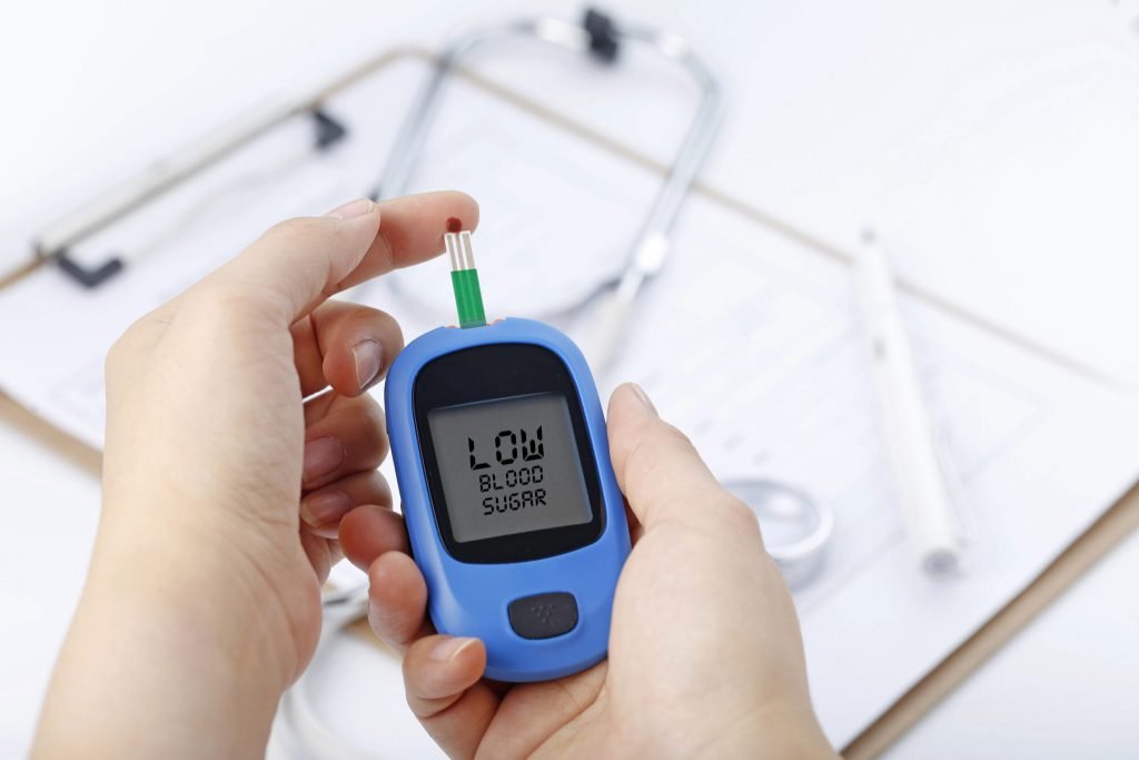Hand holding blood glucose meter measuring blood sugar background is stethoscope chart file