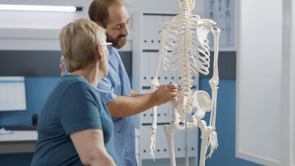 Male doctor pointing human skeleton show spinal cord explain mechanical disorders rehabilitation cabinet specialist explai...