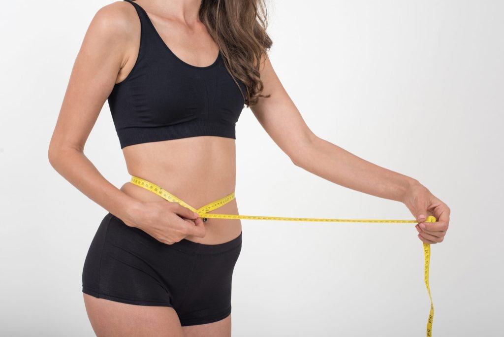 Portrait beautiful young woman measuring her figure size with tape measure