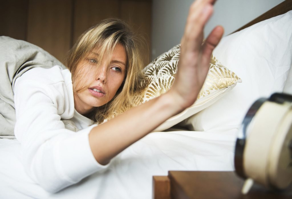 Sleepy caucasian woman turning alarm off
