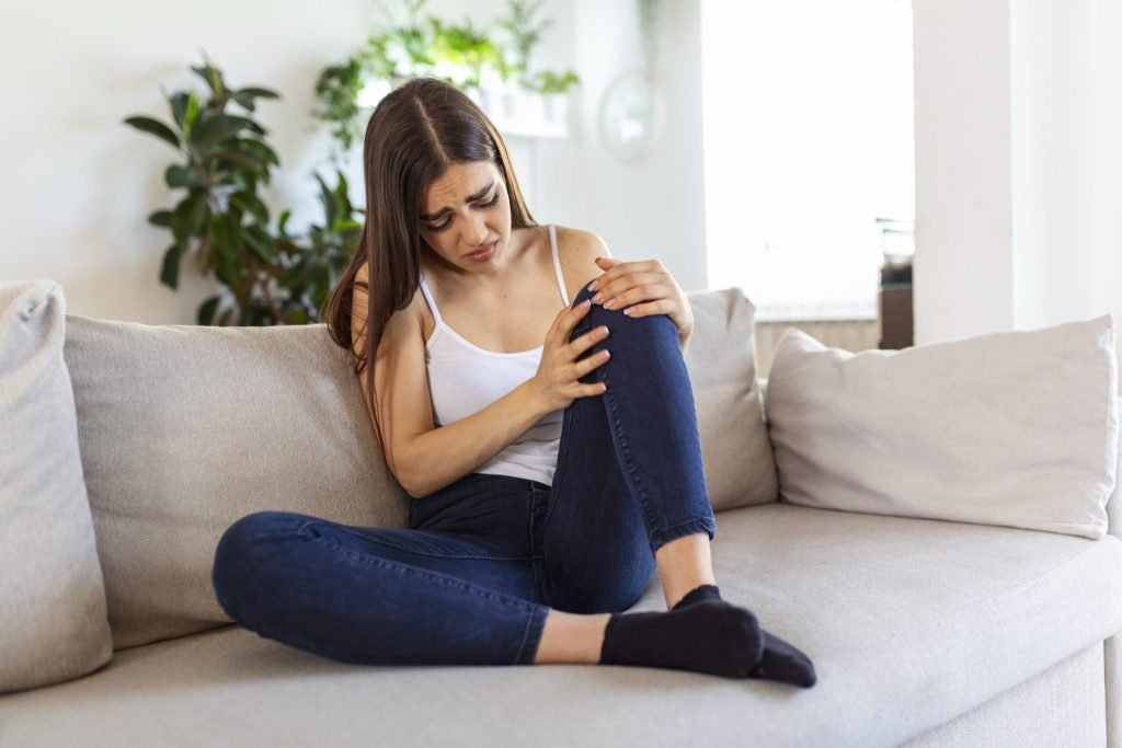 Woman holding knee with pain sofahealth care medical concept