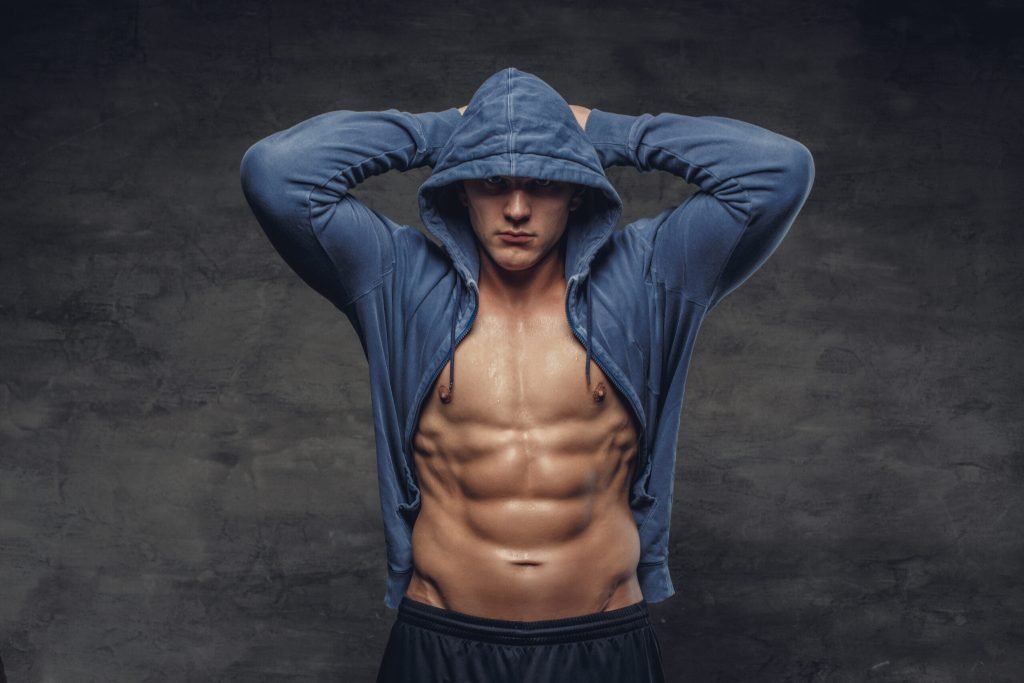 Abdominal strong man blue hoodie grey background