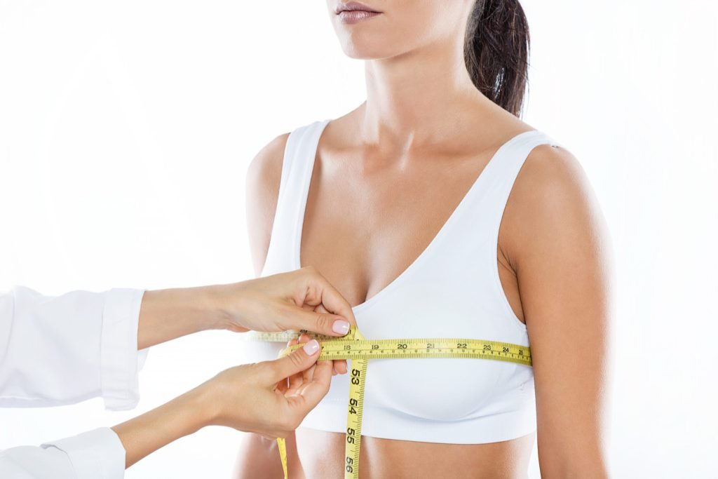 Doctor with measure tape measuring size patient s breast