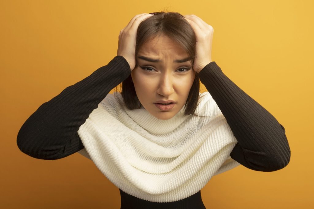 Young woman with white scarf confused with hands her head mistake