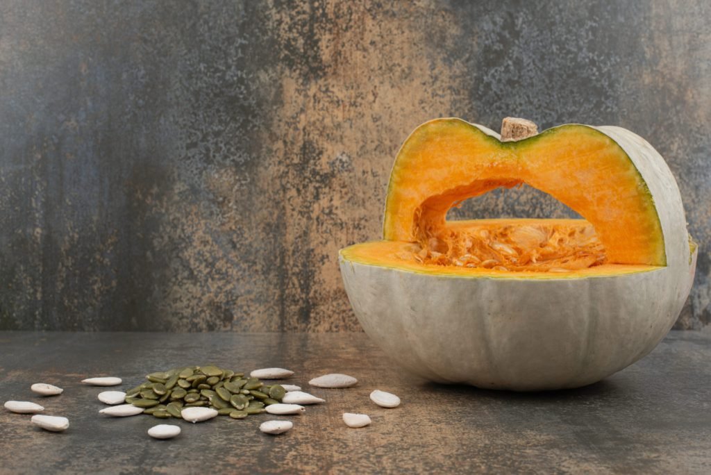 Fresh yellow pumpkin with seeds marble surface