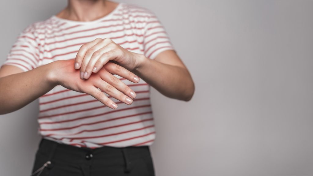 Mid section young woman having pain hand against gray background