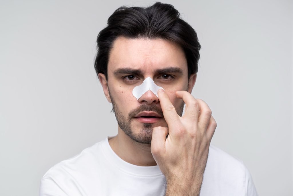 Portrait young man applying nose patch