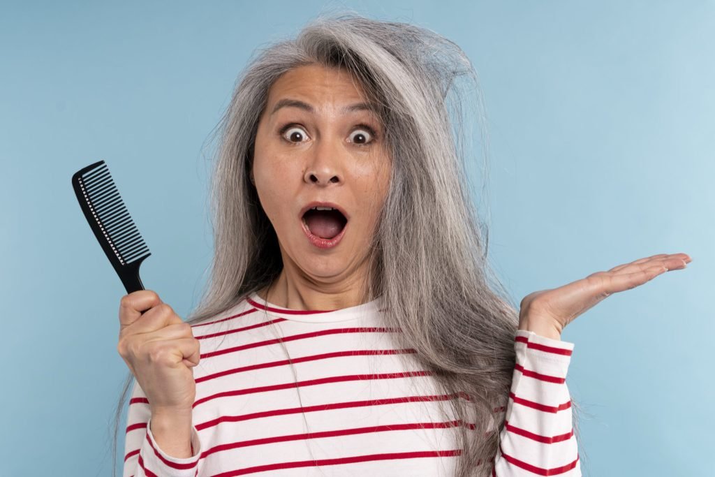 Senior woman with tangled hair being surprised against blue background