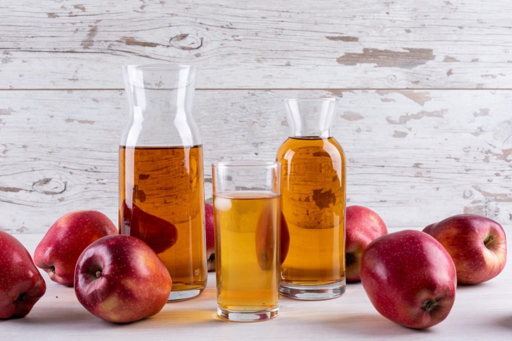 Side view apple juice with red apples white wooden table