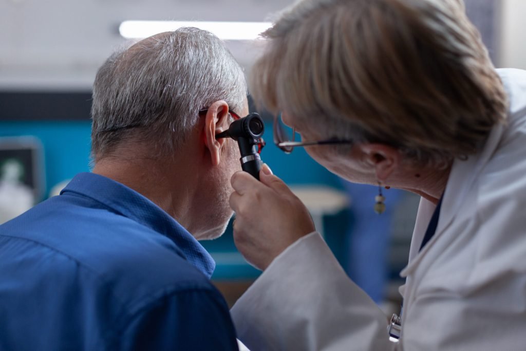Woman doctor holding otoscope ear consultation old man medical appointment otologist using otology instrument examination ...