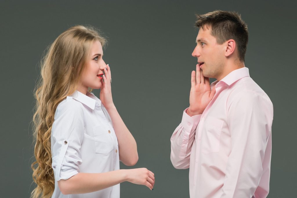 Portrait young couple standing against gray wall