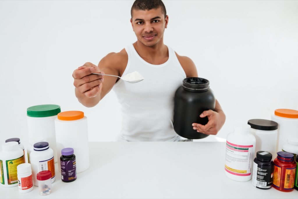 Sportsman standing white wall holding vitamins