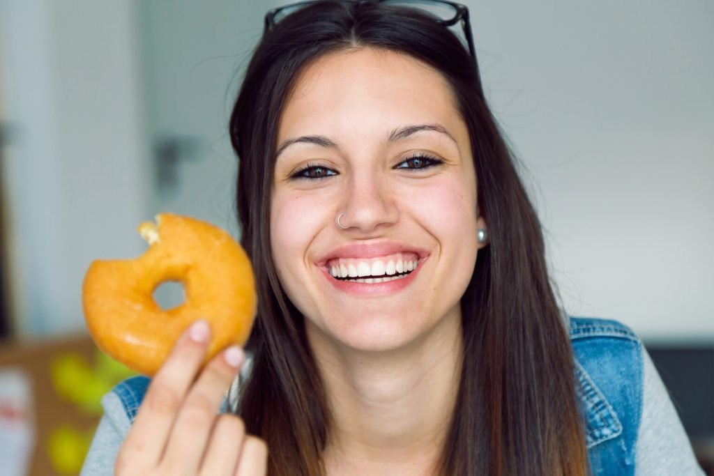 Beautiful young woman eating donuts home