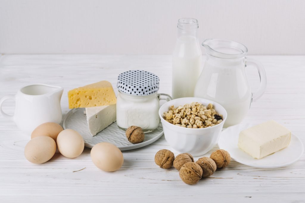Bowl cereals milk eggs cheese walnuts white textured backdrop