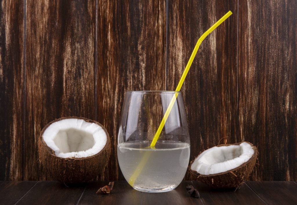 Front view halved fresh coconuts with glass water wooden surface