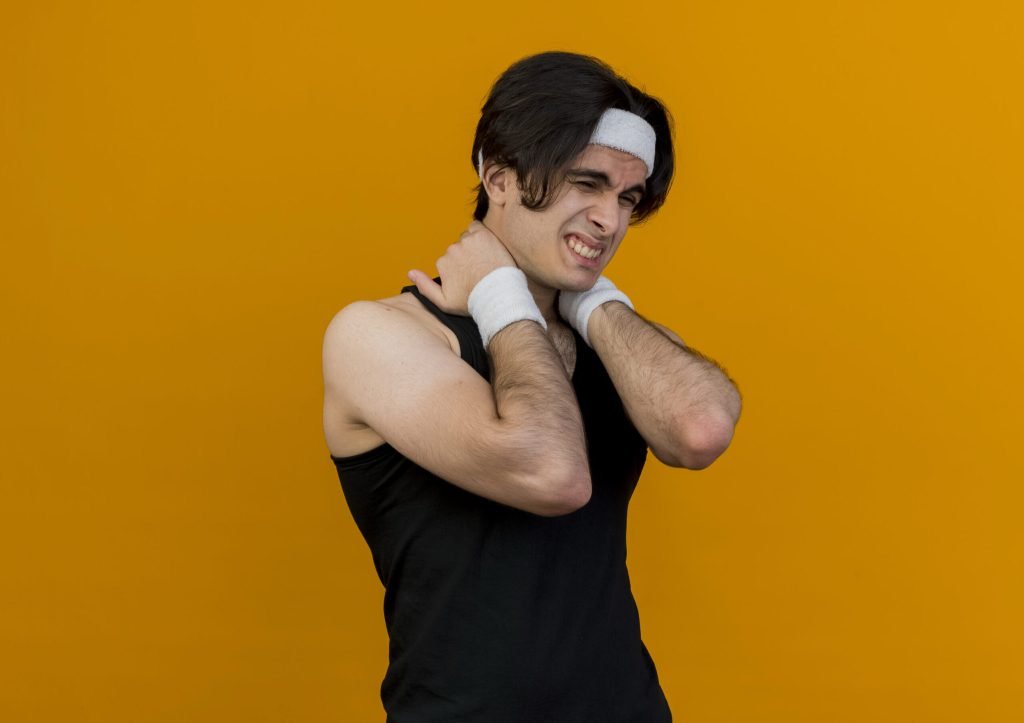 Young sporty man wearing sportswear headband touching his neck suffering from pain