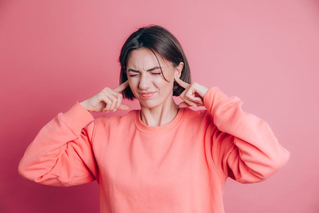 Woman wearing casual sweater background covering ears with fingers with annoyed expression noise loud music