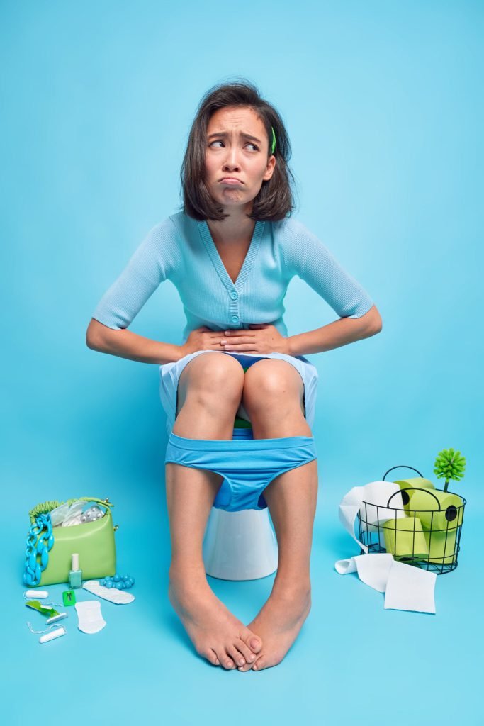 Indoor shot displeased asian woman suffers from stomachache indigestion diarrhea poses poses toilet bowl feels unwell beca...