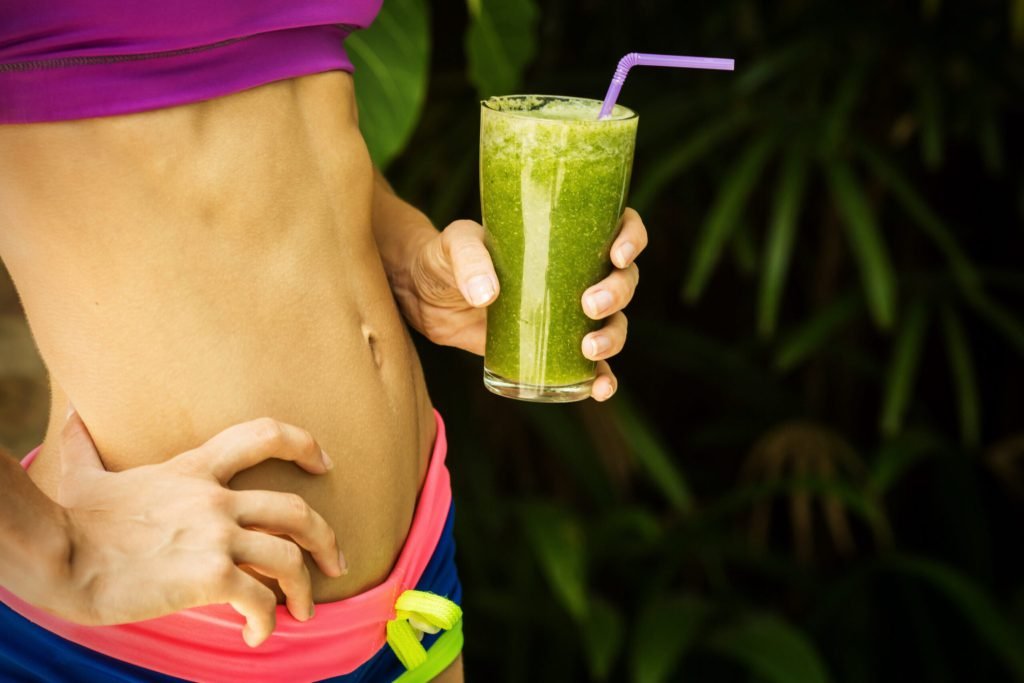 Athletic girl holding green smoothie