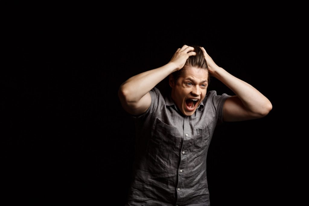 Young handsome man grab his head shouting