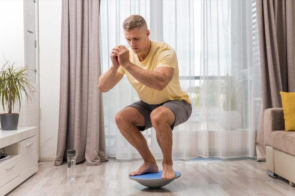 Front view man working home using bosu ball