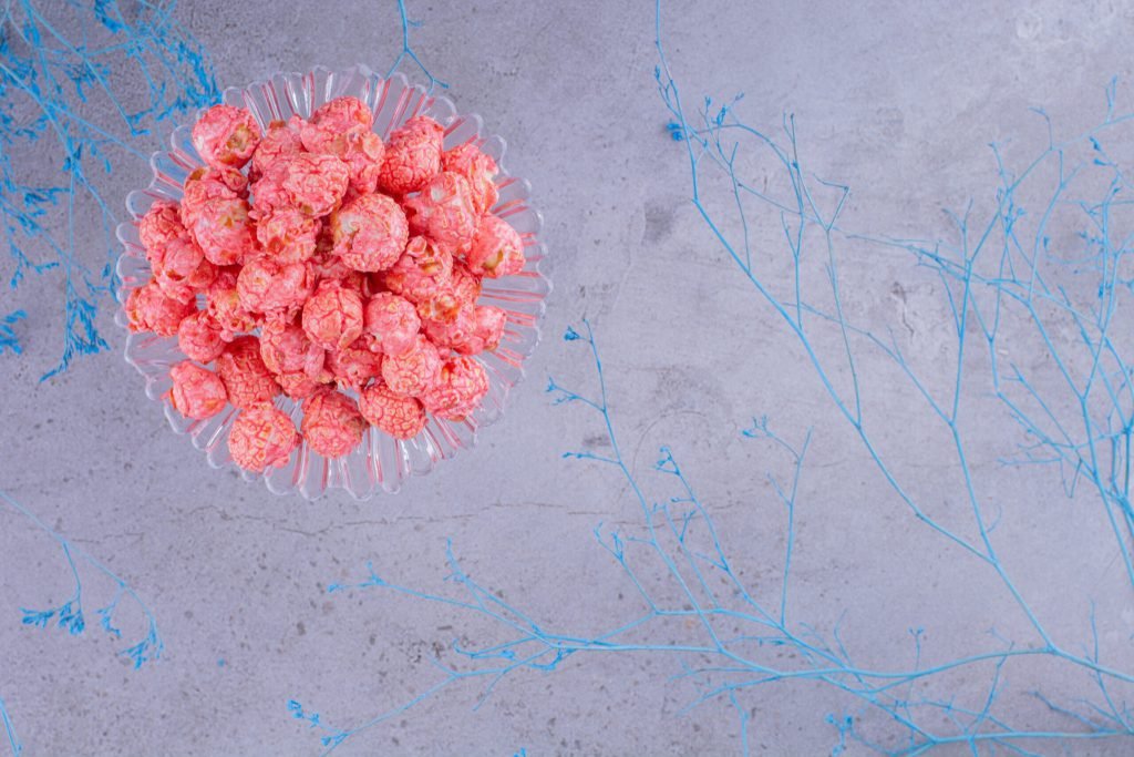 Glass holder with portion popcorn candy decorative blue branches marble background high quality photo