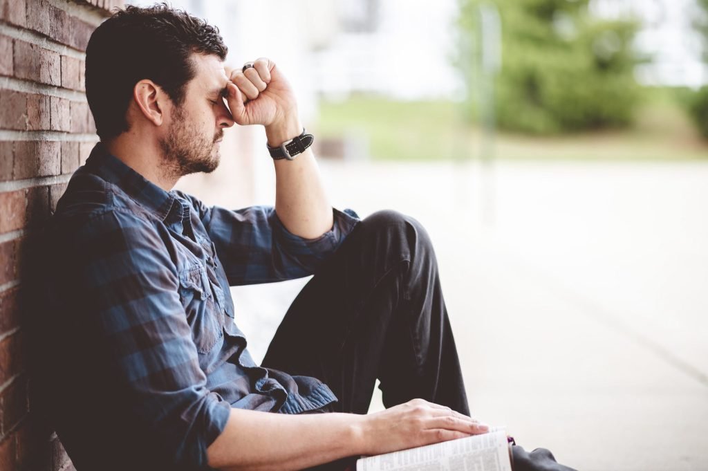 Lonely depressed person sitting near brick wall